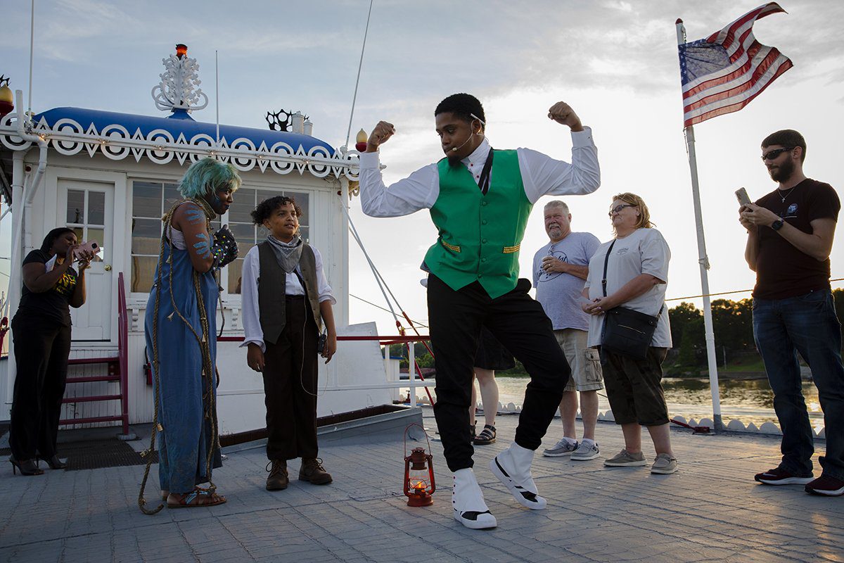 man dancing and making strong arms in green vest